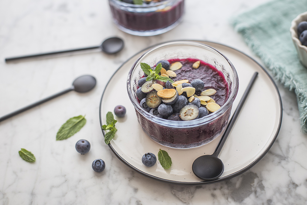 Gelatina ai mirtilli con frutti rossi freschi e lamelle o granella di frutta a guscio 